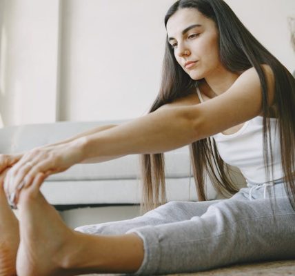 Young woman stretches on a rug in a light-filled room, embracing home fitness.